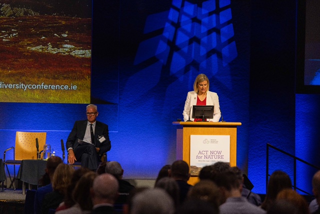 Minster Pippa Hacket speaking at a conference podium.