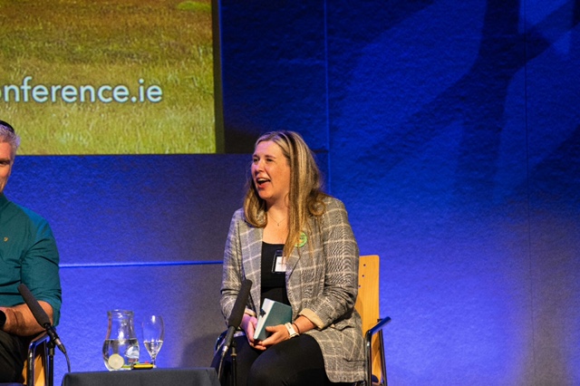 Speaker seated on a panel at a conference.