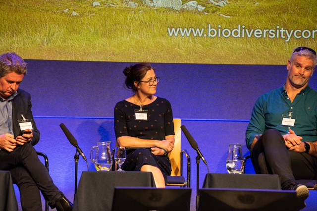 Speaker seated on a panel at a conference.