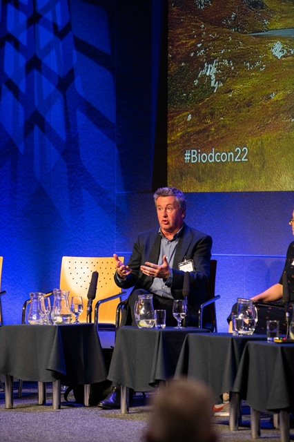 Speaker seated on a panel at a conference.