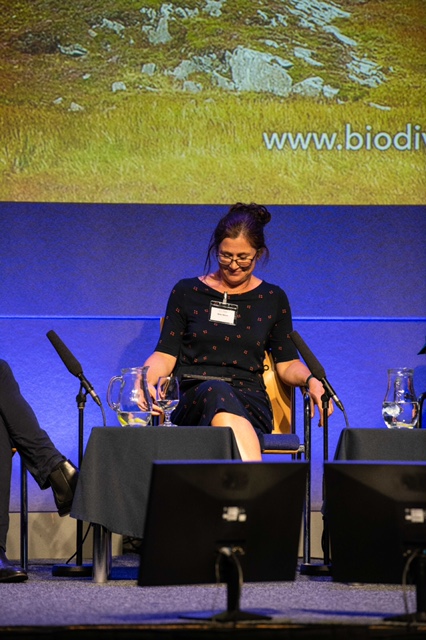 Speaker seated on a panel at a conference.