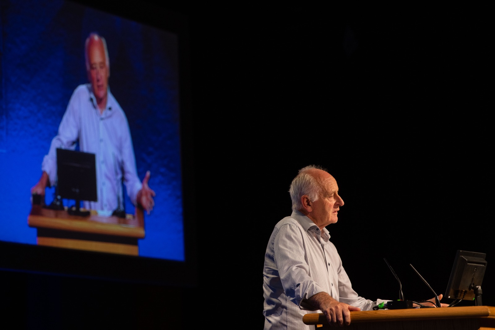 Man speaking at a conference podium.