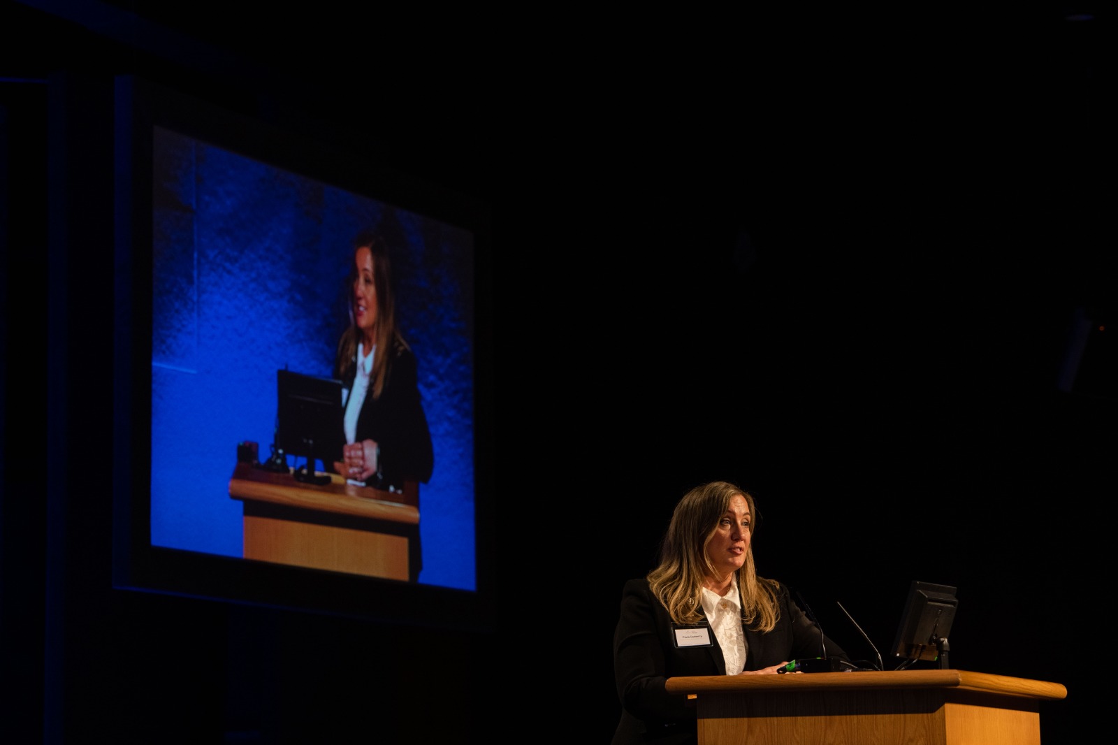 Woman speaking at a conference podium.
