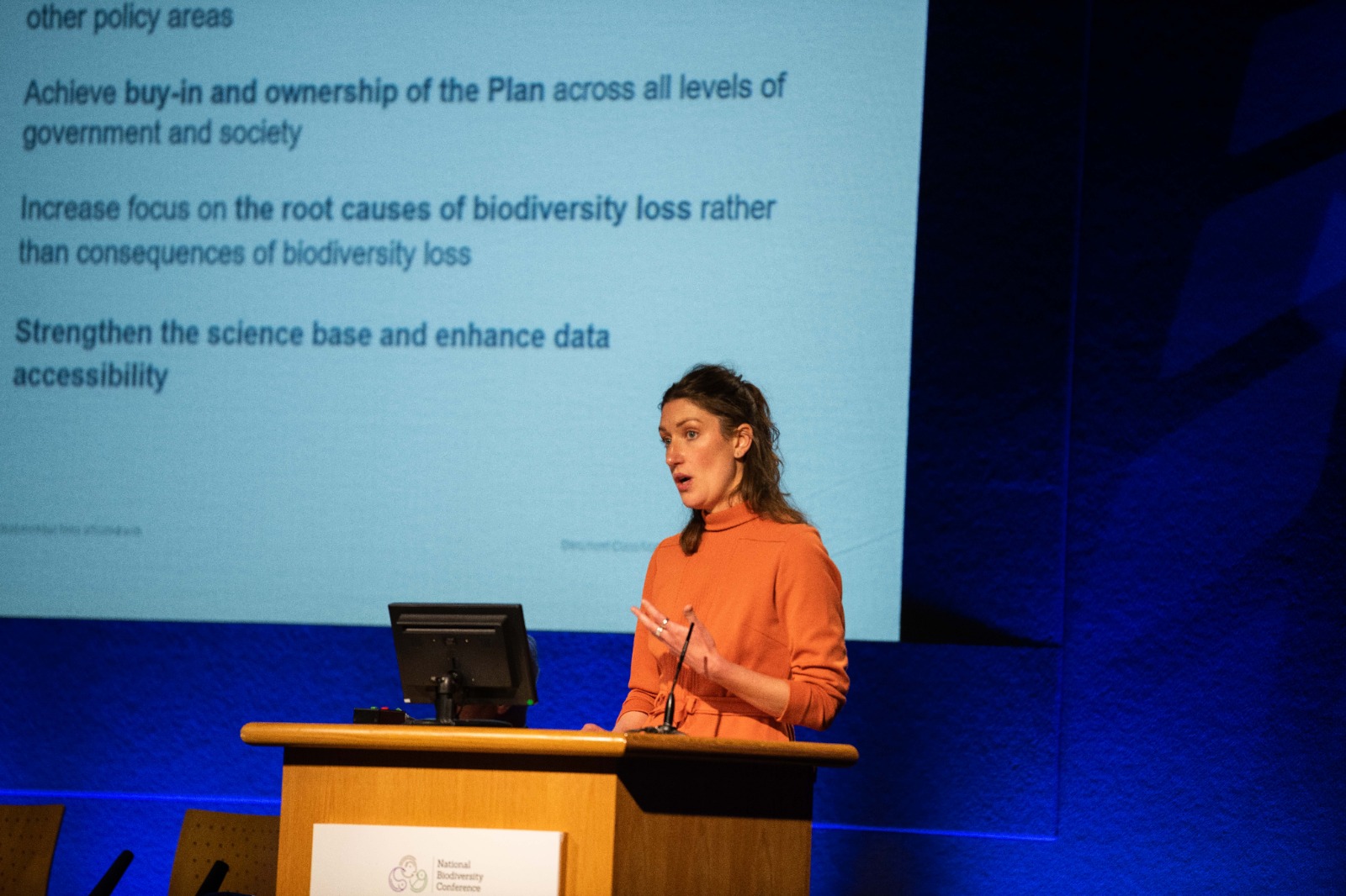 Woman speaking at a conference podium.
