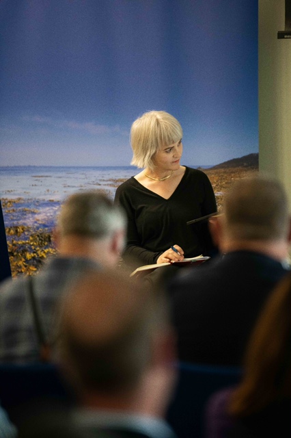Woman speaking at a conference podium.