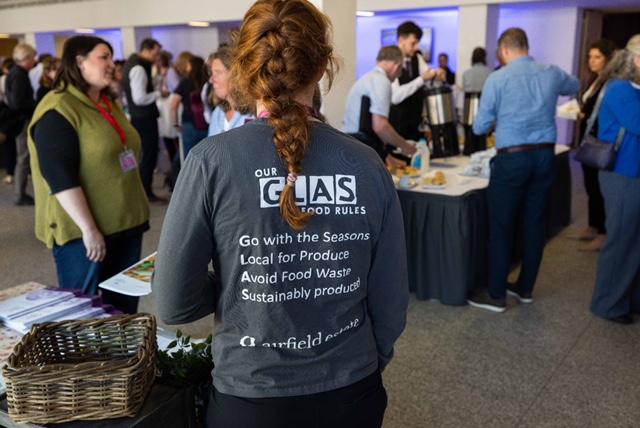 Young woman serving attendees during conference lunch.